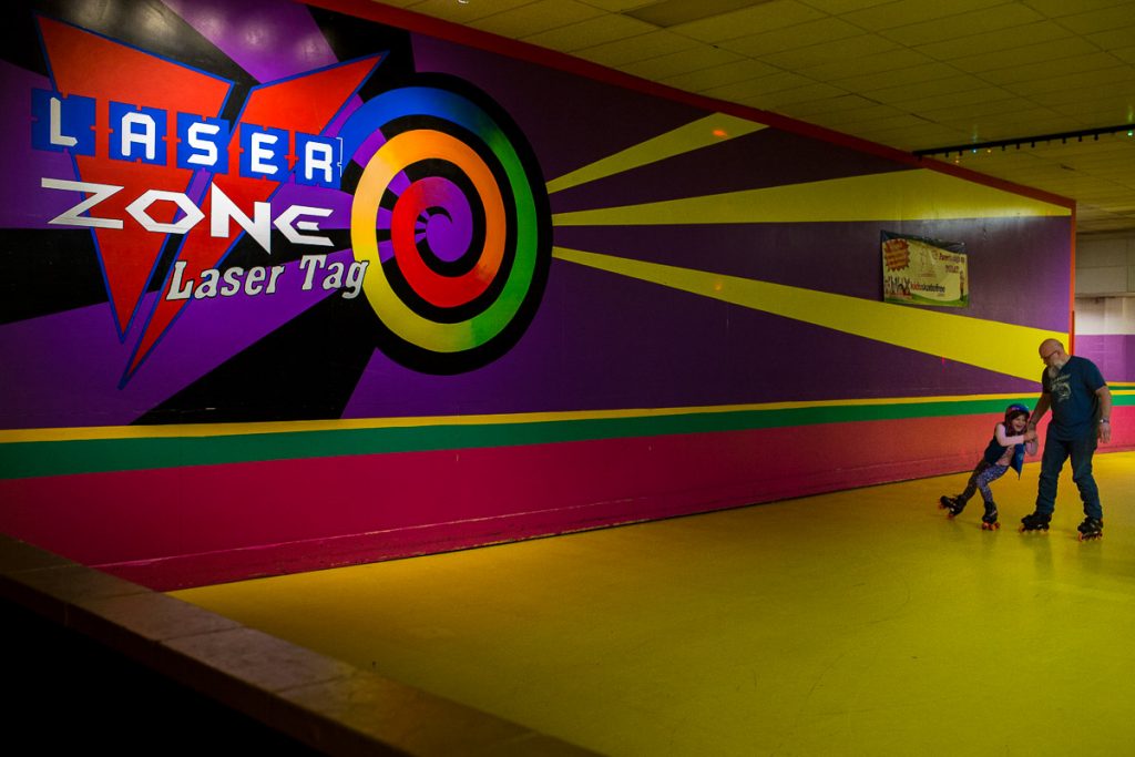 Dad is helping daughter roller skate